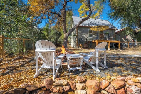 Backyard firepit surrounded by Adirondack chairs invites slow evenings under the trees, with fallen leaves underfoot and a picnic table nearby for relaxed outdoor meals or morning coffee in the fresh air.