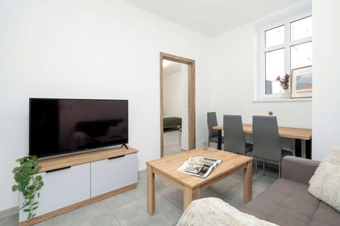 A bright living room with a comfortable sofa, TV, and dining table creates a space perfect for both relaxation and shared meals.