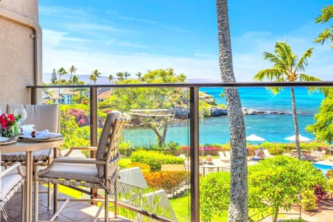 Oceanfront lanai with outdoor dining and panoramic views of turquoise waters, lush gardens, and the pool below — perfect for a tropical escape. NAP-C37