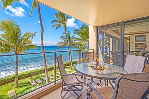Outdoor seating on a private balcony with sweeping ocean views and tropical greenery.