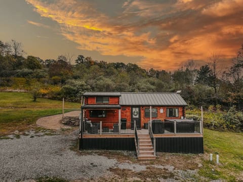 Charming cabin exterior glowing at sunset, surrounded by open grassy views