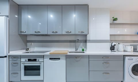 Modern kitchen featuring sleek gray cabinets, white countertops, and essential appliances.