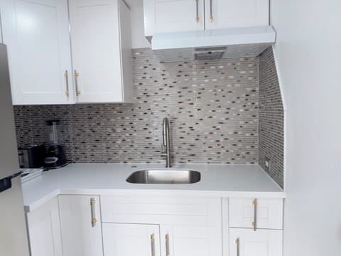 Your private kitchen features gleaming white cabinets and elegant mosaic backsplash that catches the light beautifully. You'll love preparing meals with modern appliances and plenty of counter space.