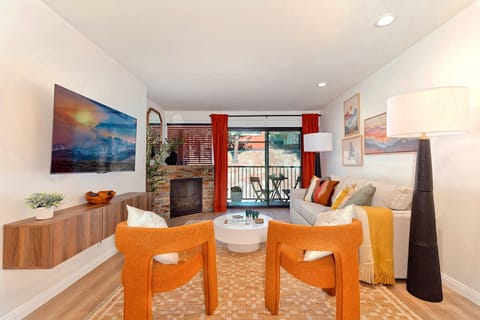 Cozy living room with thermostat-controlled gas fireplace, Smart TV, and balcony