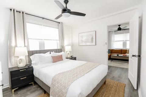 Bedroom with end tables, lamps, ceiling fan, and a large window. 