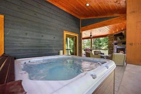 Private hot tub on covered deck with fireplace and peaceful forest views