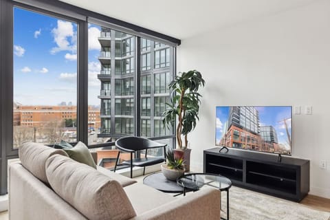 Unwind on the plush sofa beside bright skyline windows.