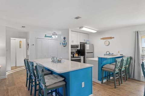 Gather around your spacious coastal-themed kitchen island where bright blue cabinets and beachy decor create the perfect spot for family meals and vacation memories.