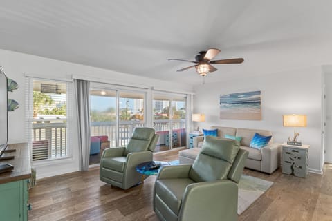 Unwind in your coastal-inspired living room with plush recliners and ocean artwork creating the perfect beach vacation atmosphere.