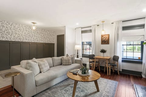 A view from the living room toward the entry reveals the dedicated workspace beside the fireplace mantel, colorful vintage Savannah art prints, and the open layout that connects every room.