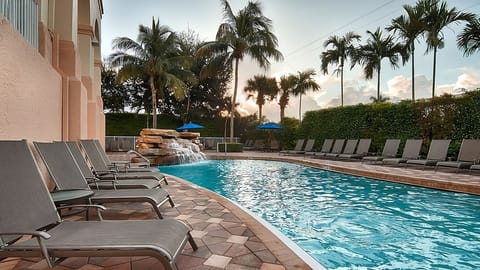 Unwind at golden hour with loungers and waterfall sounds.