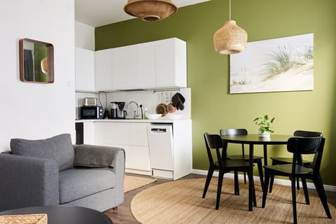 The apartment features an eye-catching olive green accent wall that brings life and warmth to the space.