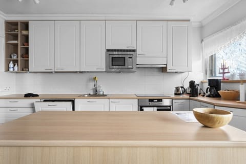 The kitchen is fully equipped with an induction cooktop, oven, microwave, dishwasher, and all necessary small appliances like a coffee maker and electric kettle.