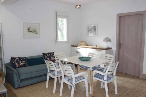 Relax in a cheerful, air-conditioned space featuring coastal décor, dining table, and easy access to the terrace.