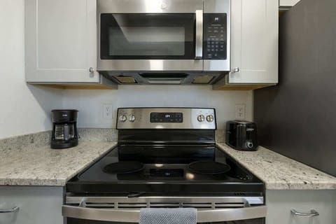 Modern kitchen setup featuring stainless steel appliances, granite countertops, and essentials like a coffee maker and toaster — perfect for convenient cooking.