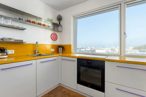 A corner kitchen with bright yellow countertops, modern appliances, and a panoramic city view. The design feels energetic.