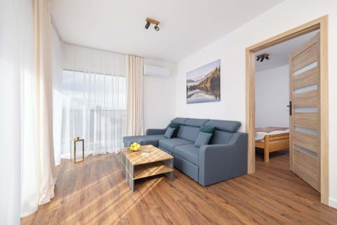 A bright living room with a blue sofa and large windows that fill the space with natural light. The room offers a warm and inviting atmosphere, perfect for relaxation.