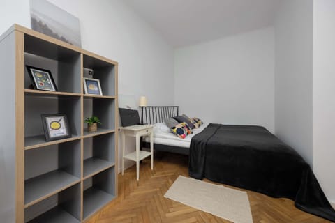 A cozy bedroom corner featuring a double bed with dark bedding and a gray shelving unit.