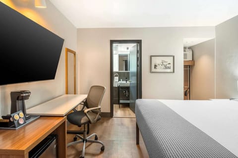 Work desk with coffee maker and large TV facing the bed