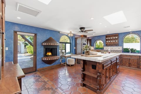 Fully equipped kitchen with stainless steel appliances, a sleek kitchen island, ample counter space, and a gas fireplace.