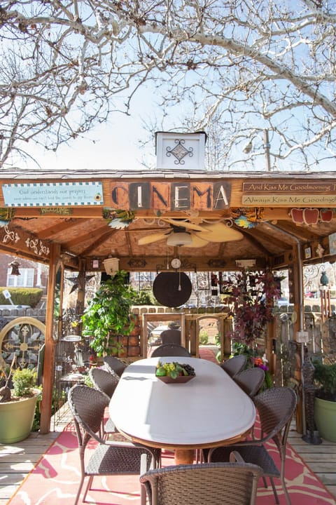 Charming enclosed outdoor dining gazebo with ceiling fan and festive décor, ideal for relaxing evenings