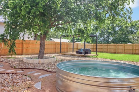 Soak under the shade of a grand tree in your private stock-tank pool, with a pergola seating area ready for lounging in your peaceful, fully-fenced backyard retreat.