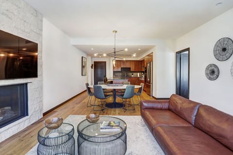 Inviting lounge with stone-framed fireplace, twin coffee tables, and balcony access for mountain sunsets.