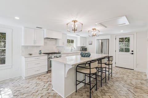Your spacious gourmet kitchen features gleaming white cabinetry, premium stainless steel appliances, and elegant pendant lighting that creates the perfect ambiance for cooking memorable meals.
