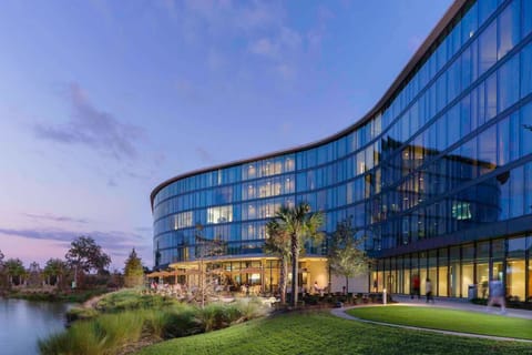 The inviting exterior of Hotel ELEO features expansive windows that open to wellness spaces, blending luxury with a calming lakeside atmosphere.