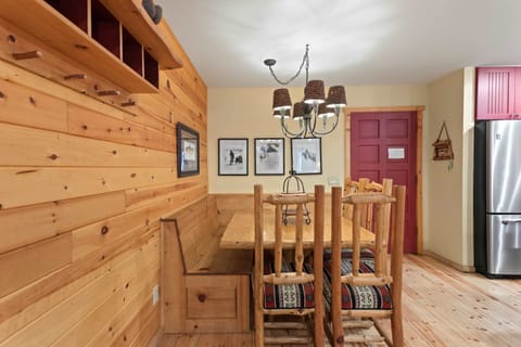 Rustic pine dining bench seats 8 under a charming pinecone chandelier.