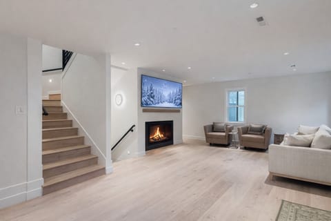Relax in this cozy living space, perfect for movie nights with two wall-mounted TVs and a warm, inviting fireplace.