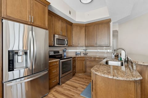 Fully equipped kitchen with warm cabinetry, granite counters, and stainless appliances.