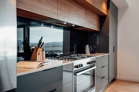 Modern kitchen equipped with a cooktop, oven, dishwasher, coffee machine, and kettle for your convenience.