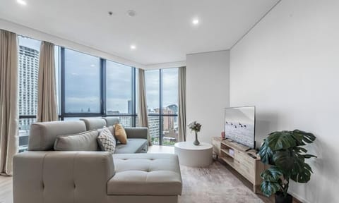 A spacious, sunlit living area featuring a comfortable grey sectional sofa