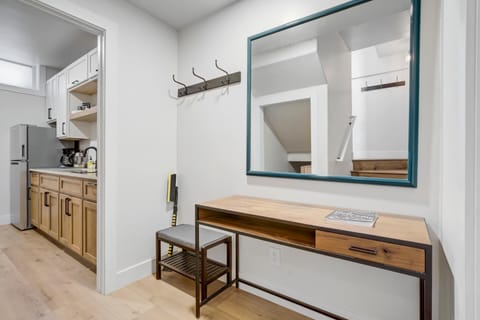 The entry hall features a convenient drop zone with hooks, seating, and a large mirror for quick organization. It flows naturally toward the kitchenette, giving the suite a practical and comfortable layout from the moment you walk in.