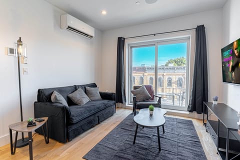 Scandinavian living room with smart TV, sofa and soft lighting in calm Bushwick 1BD loft