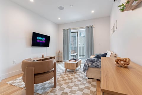 Scandinavian living room with smart TV, sofa and soft lighting in calm Bushwick 1BD loft