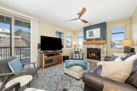 Unwind in your cozy living room with crackling fireplace, plush seating, and mountain views through floor-to-ceiling windows.