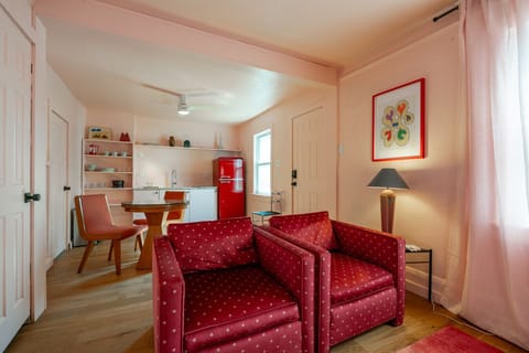 Living Room View: Cozy pink-toned lounge with bright natural light and mid-century charm.