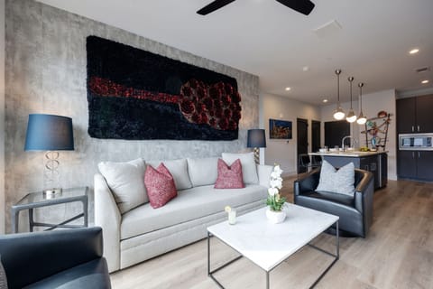 Unit 1: Modern open concept living area with floor to ceiling windows, designer furniture, smart TV, and access to private patio.