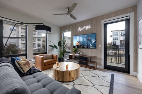 Unit 1: Bright open living space featuring a smart flat-screen TV, designer furnishings, and access to the private patio.