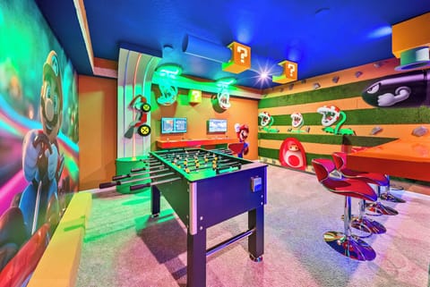 Experience our lively game room with a foosball table and colorful murals that spark nostalgia. The bright blue ceiling and unique bar stools set the perfect backdrop for fun and relaxation with friends and family.