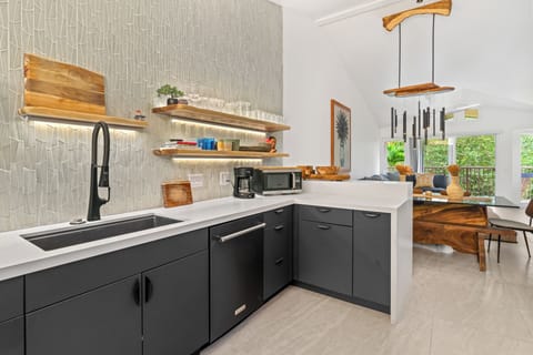 Live-edge shelving and black matte cabinetry bring style and function to the kitchen.