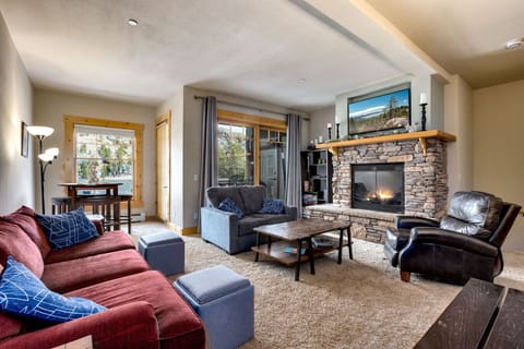 Relax by the fireplace in this cozy living room, offering a perfect space to unwind after a day of outdoor adventures. Enjoy scenic mountain views from the large windows.