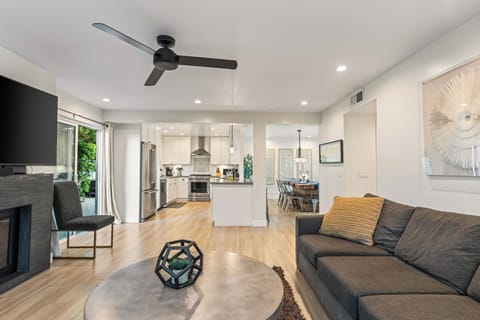 The living room is connected to the kitchen with a ceiling fan, TV, and sofa.
