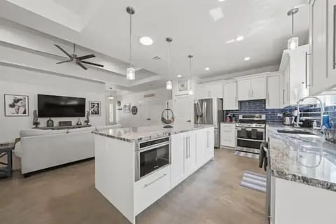 A bright, modern kitchen with a large island, stainless steel appliances, and sleek white cabinetry.