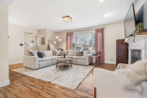 Bright living room w/ cozy seating, warm wood floors & large windows letting in natural light.