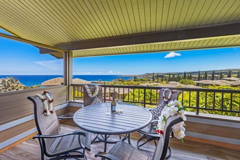 Dine alfresco on a private lanai with a round table and chairs, overlooking sweeping ocean views under a shaded roof.