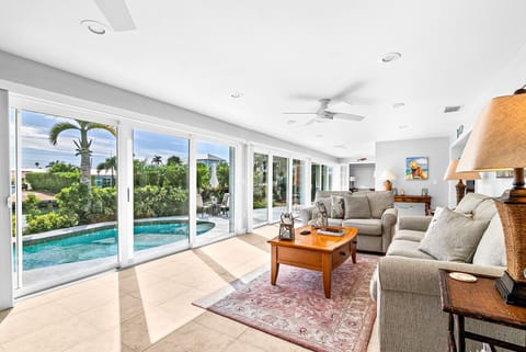 Step into your bright, airy living space where floor-to-ceiling windows frame stunning pool and garden views. Sink into plush seating while tropical breezes flow through, creating the perfect indoor-outdoor oasis.