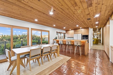 A bright, open dining and kitchen space blends warm wood finishes with expansive views for a stylish, inviting atmosphere.